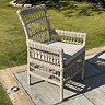 image of beige wicker chair with plush seat cushion on patio alone