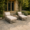 lifestyle image of two neutral wicker sun loungers outside stately house