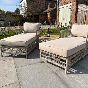 close up image of two beige sun loungers with square coffee table between them
