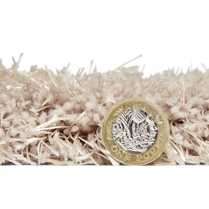 side on image of rug with pound coin stood next to it to show rug as just a bit taller than coin's height