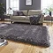 image of dark grey shaggy rug in front of light grey sofa with grey accent cushions