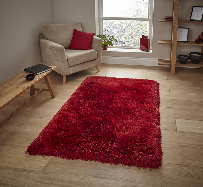 image of red fluffy rug on light wood flooring next to armchair with red accent cushion