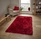image of red fluffy rug on light wood flooring next to armchair with red accent cushion