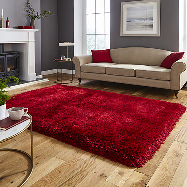 image of red fluffy rug on light wood flooring next to armchair with red accent cushion