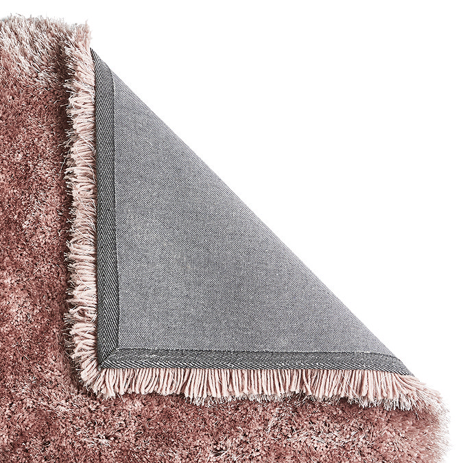 pink shaggy rug folded over in the corner to show floor-facing material underneath