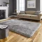 image of silver shaggy rug in front of beige sofa with grey cushions