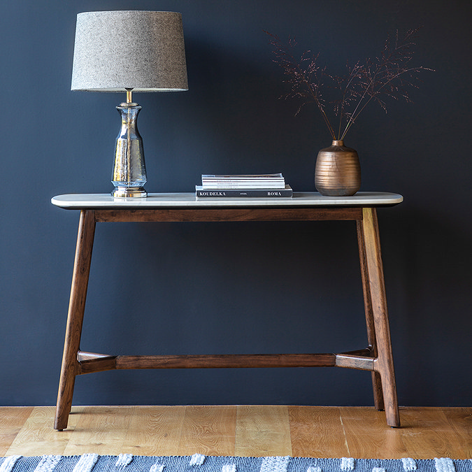 image of marble oval console table on dark wood legs, against teal wall