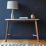 image of marble oval console table on dark wood legs, against teal wall