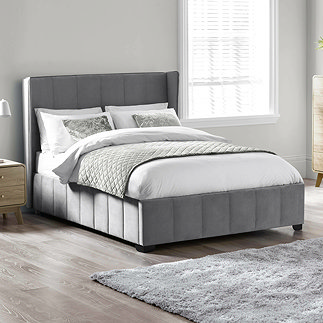 image of grey panelled velvet bedframe with subtle winged headboard, dressed in plush duvet, on wooden floor of bedroom