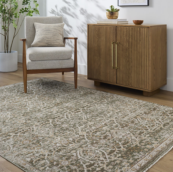 image of olive green vintage rug  with floral pattern in subtle greens and browns, on wooden flooring