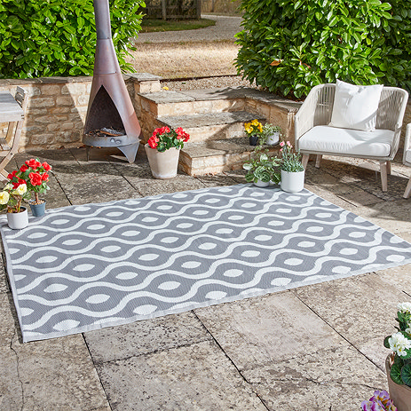 image of abstract patterned rug in slate grey, on patio with bright flowers