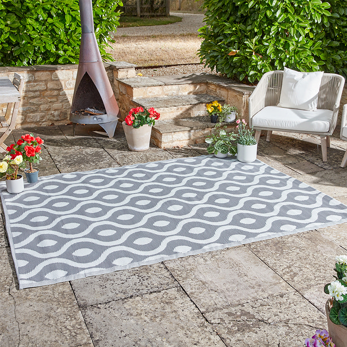image of abstract patterned rug in slate grey, on patio with bright flowers