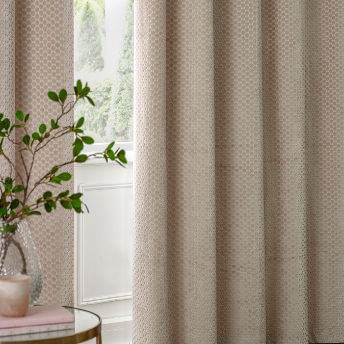 Neptune Eyelet Curtains in champagne over a window close up image