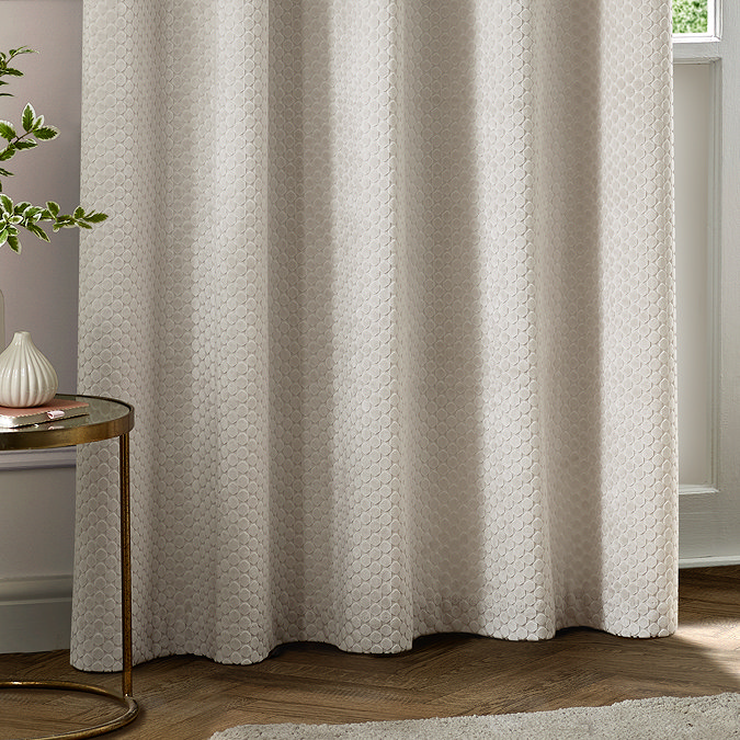 Neptune Eyelet Curtains in Ivory over a window close up image