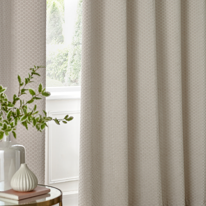 Neptune Eyelet Curtains in Ivory over a window close up image
