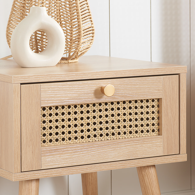 close up image from the side of a light oak rattan bedside table
