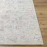 close up image of corner of traditional oriental rug with floral patterns in tan and grey colours