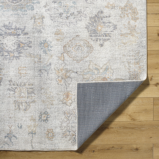 close up image of corner of floral grey-blue vintage rug folded over to show material underneath
