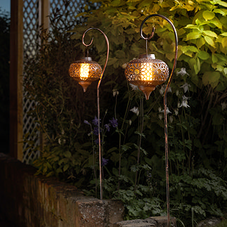 image of two tall metal lanterns on a crook, lit with LED flame inside