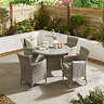 image taken slightly above of round bistro dining set with four rattan chairs, on a back patio in the sun