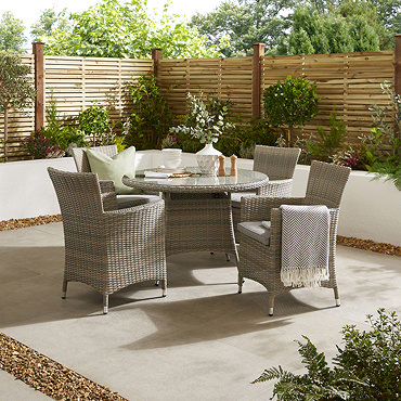 image taken slightly above of round bistro dining set with four rattan chairs, on a back patio in the sun