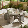 image angled from slightly above, looking over round garden table with six matching rattan chairs, on a stone patio