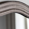 close up image of arched top of soft grey mirror with decorative detail