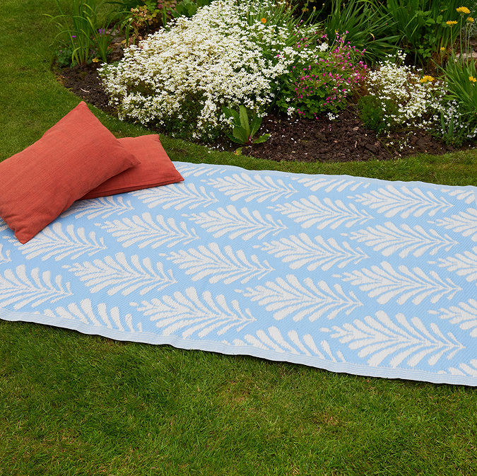 image of sky blue leaf patterned rug on grass with cushions