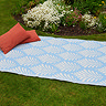 image of sky blue leaf patterned rug on grass with cushions