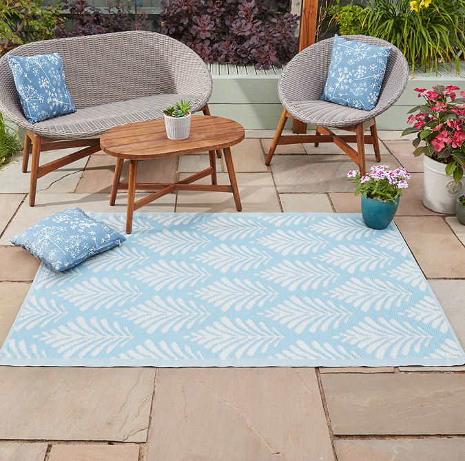 image of rectangular sky blue rug patterned with white leaves on patio