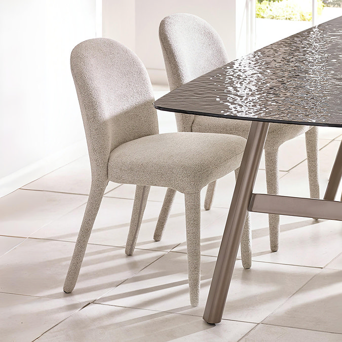 image of two beige chenille dining chairs tucked on one side of a black textured rectangular dining table