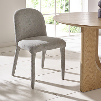 image of single light grey chenille dining chair next to round wooden table