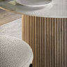 close up image of boucle dining chair tucked under ribbed mango wood dining table, marble tabletop shown just at the top of the image