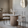 image of round ribbed fluted mango wood dining table with marble tabletop, on cream rug of dining table and two modern chairs tucked on either side of it