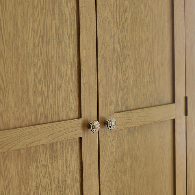 close up image on closed doors of classic oak wardrobe with small delicate metal handles