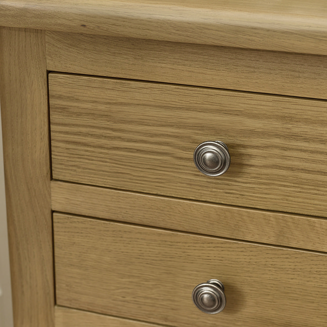 close up image of solid oak front and small round metal handles of three drawer bedside table