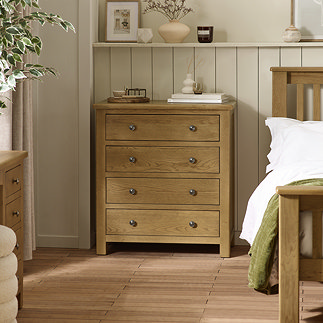 image of 4 drawer solid oak chest next to matching bed in modern country style bedroom