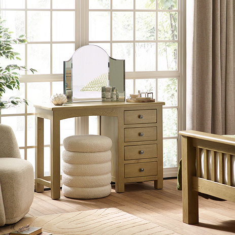 image of solid oak dressing table with four drawers on the right hand side with cream pouffe stool tucked under it