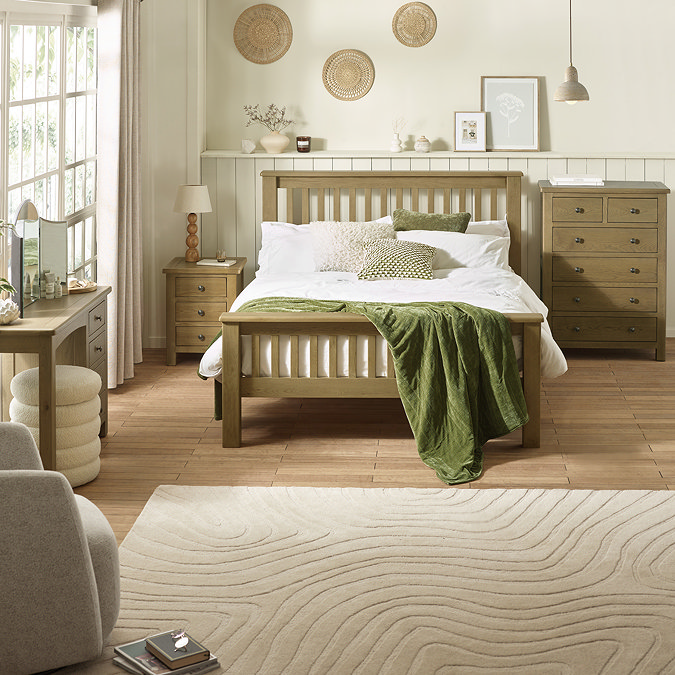 wide image of solid oak slatted bed with matching side table, dressing table and six drawer chest