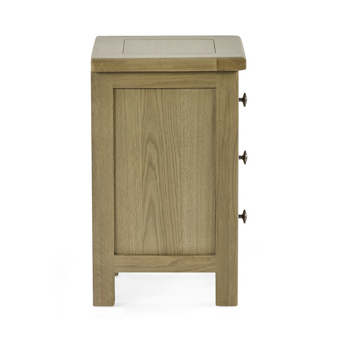 side on image cut out on white background of slim three drawer oak bedside table