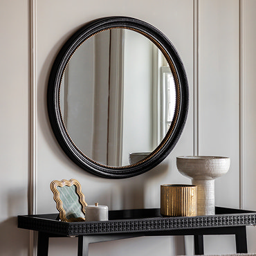 close up image of black round wall mirror with gold inner trim detailing