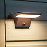 close up image of motion sensor security light attached to the outside of garden shed, emitting warm light