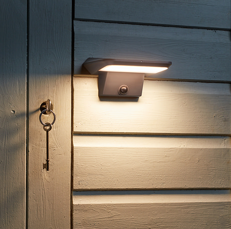 image of motion sensor light attached to outside of a shed, emitting warm glow onto lock