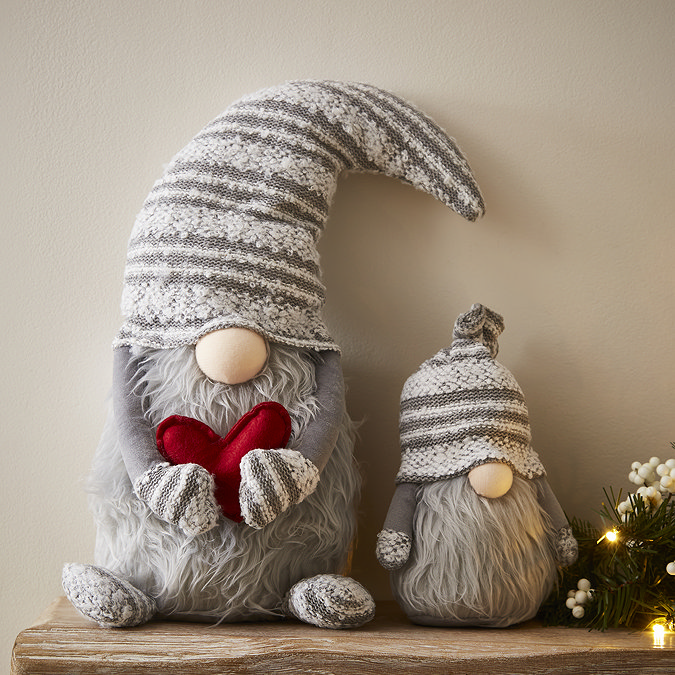 plush grey gonk with heart, sat next to smaller grey gonk on a light wood mantlepiece