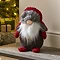 plush grey gonk santa with red wool hat sat on the hearth