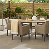 close up image on left side of garden dining set, rattan chairs under a wooden table, one chair with yellow throw draped over the back of it