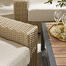 close up image on chunky rattan armchair and slatted wooden table of corner sofa set