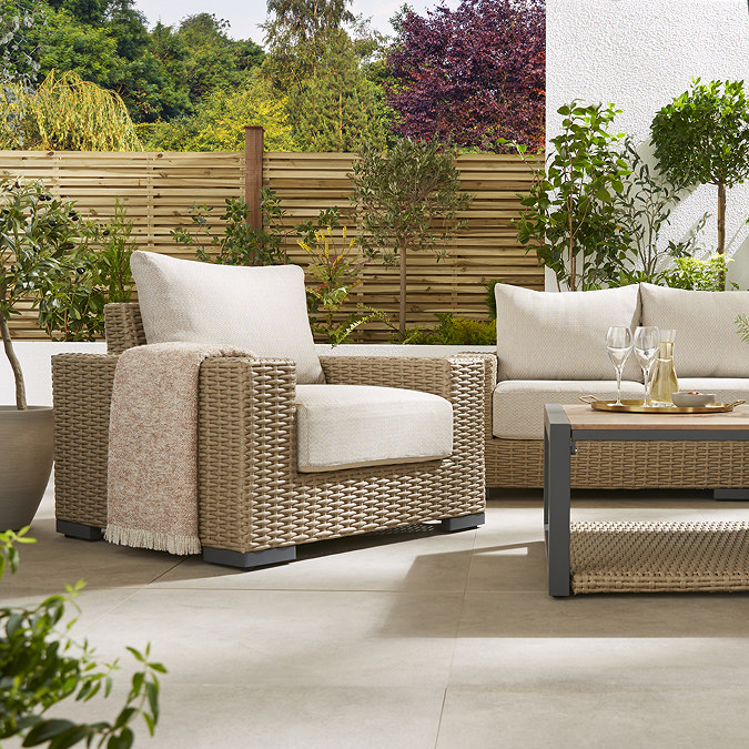 close up image of chunky rattan garden armchair with cream cushion