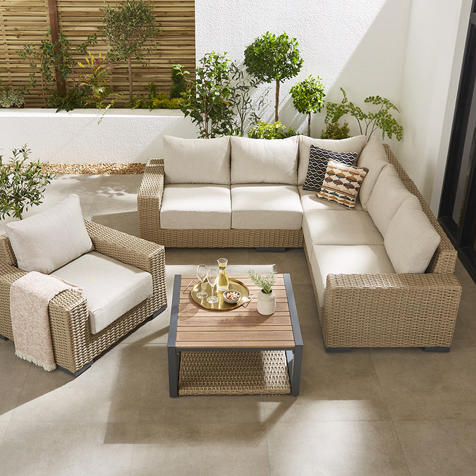 image taken from slightly above of luxury rattan corner lounge set with plush cream cushions, a matching armchair, and slatted coffee table