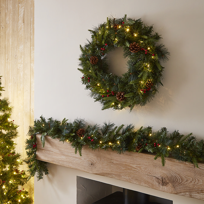 wider image of cranberry and pine garland on a mantlepiece, with wreath hanging above